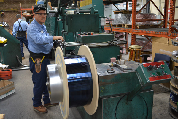Tool King employee working with blue polished spring steel coil